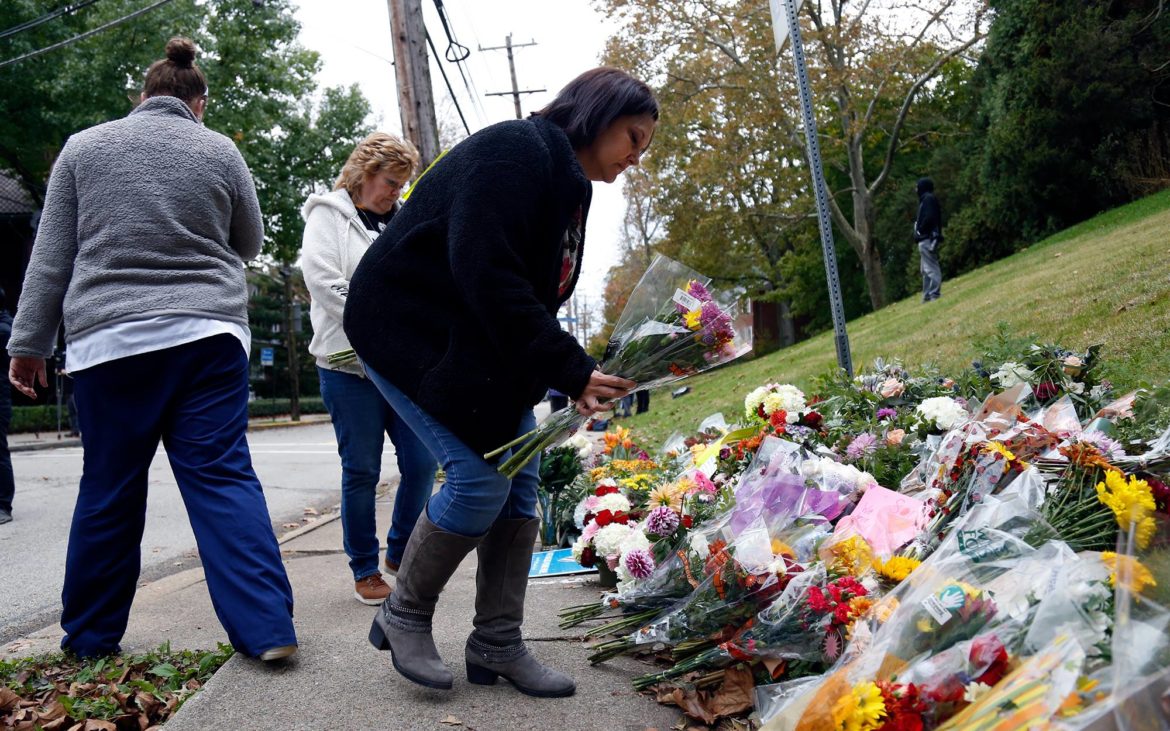 Dawn Schempp, 45, of Munhall, leaves flowers at a memorial at the intersection of Murray and Wilkins avenues in Squirrel Hill. (Photos by Daniel Barnhill and Heather Mull/PublicSource)