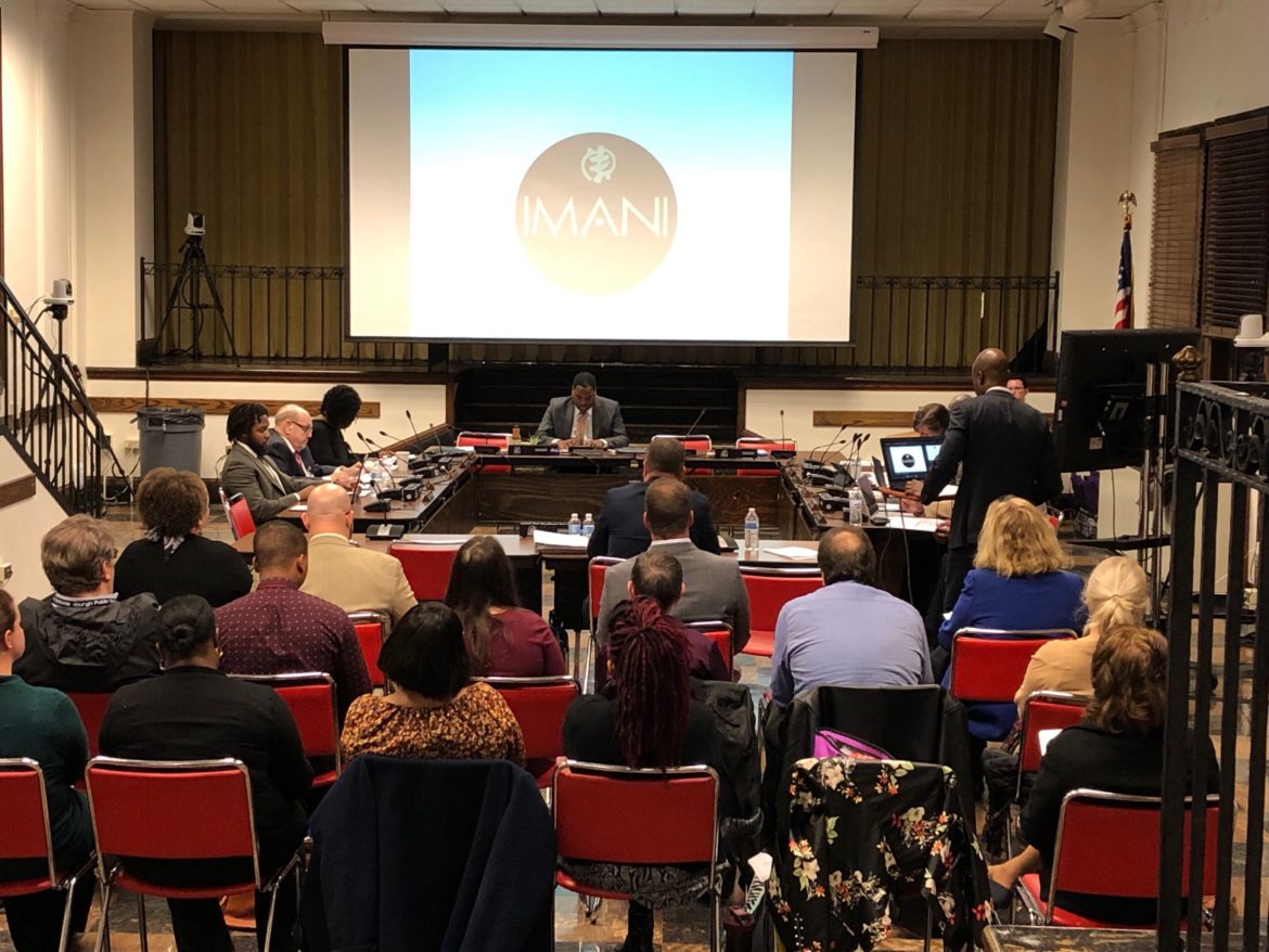 Imani CEO/Head of School Paulo Nzambi (right) addresses the Pittsburgh Public Schools board on Tuesday evening. (Photo by Mary Niederberger/PubliSource)