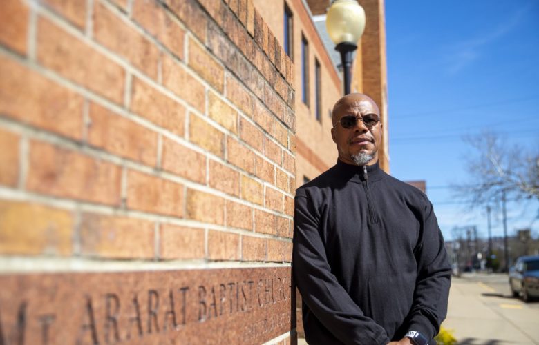 Rev. Curtis stands against a wall outside Mount Ararat Baptist Church