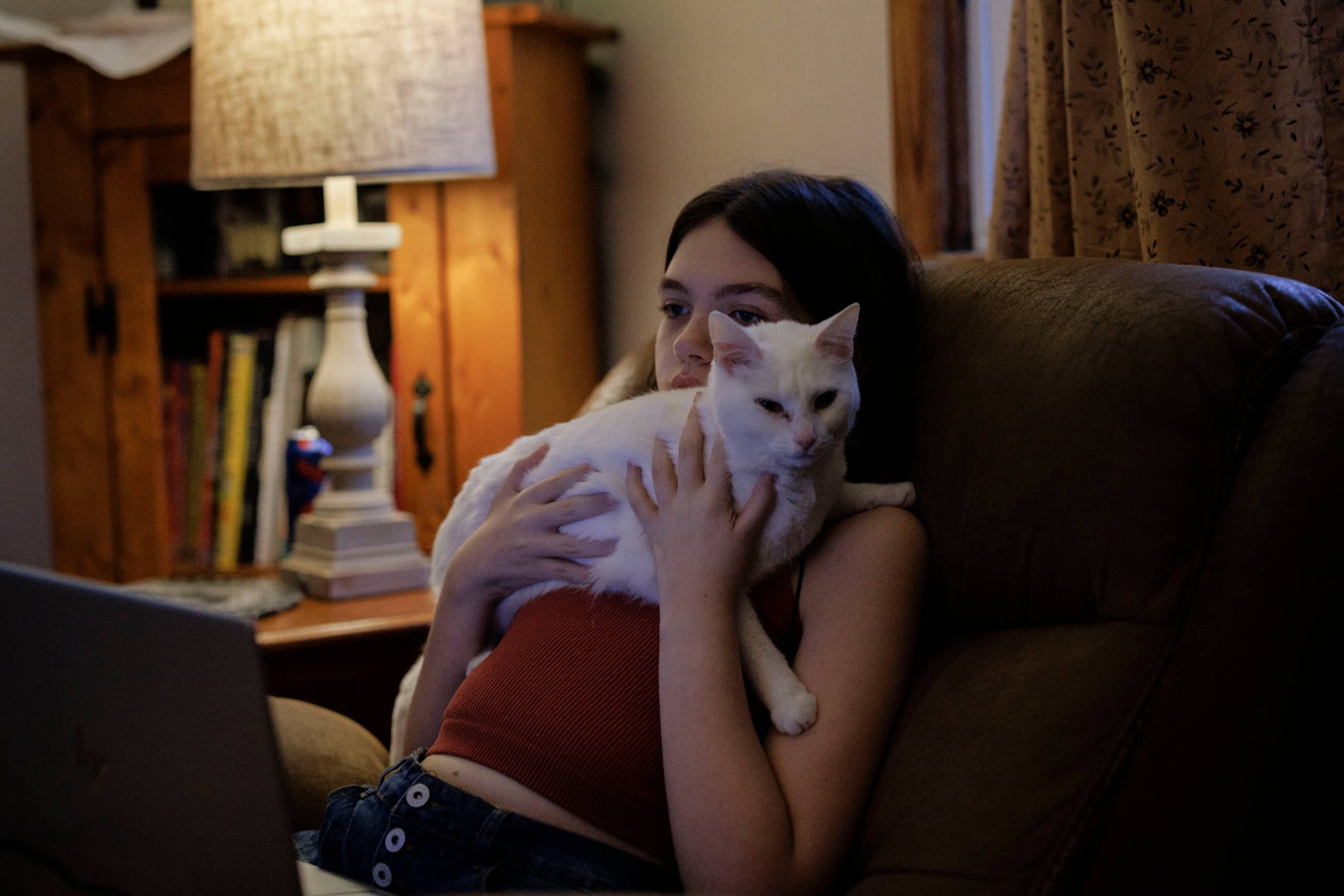 A girl sitting in a chair holding a cat.