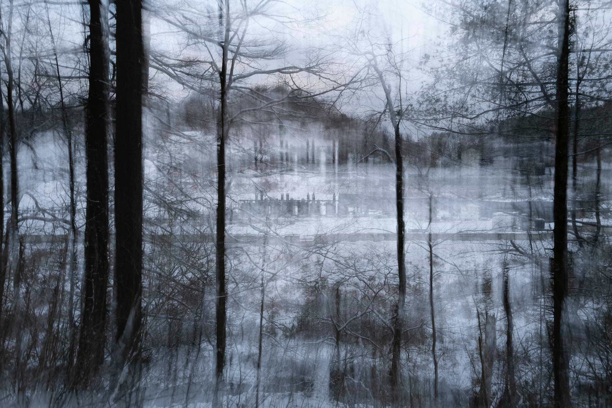 A long-exposure image of trees and a well pad in the snow.