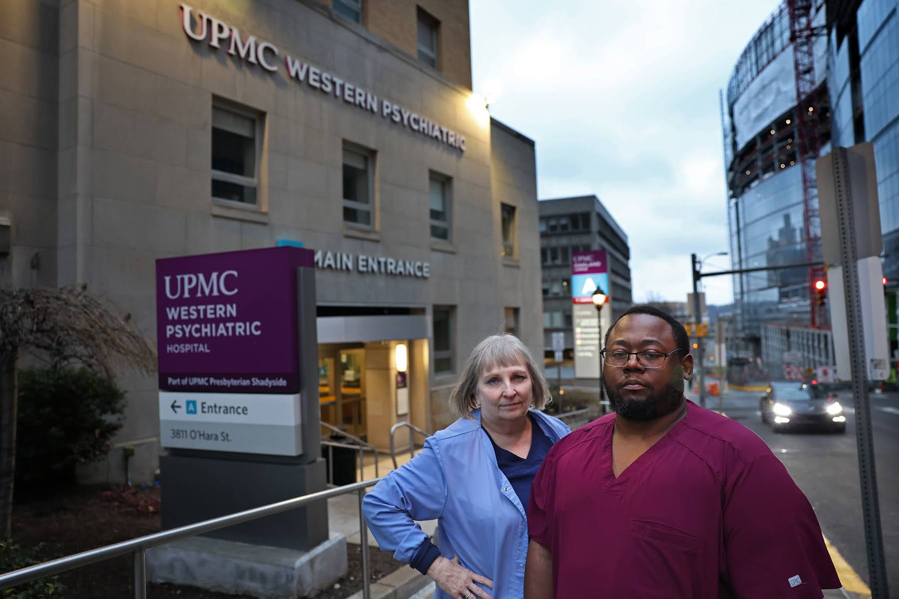 Two nurses in scrubs stand outside UPMC Western Psychiatric Hospital.