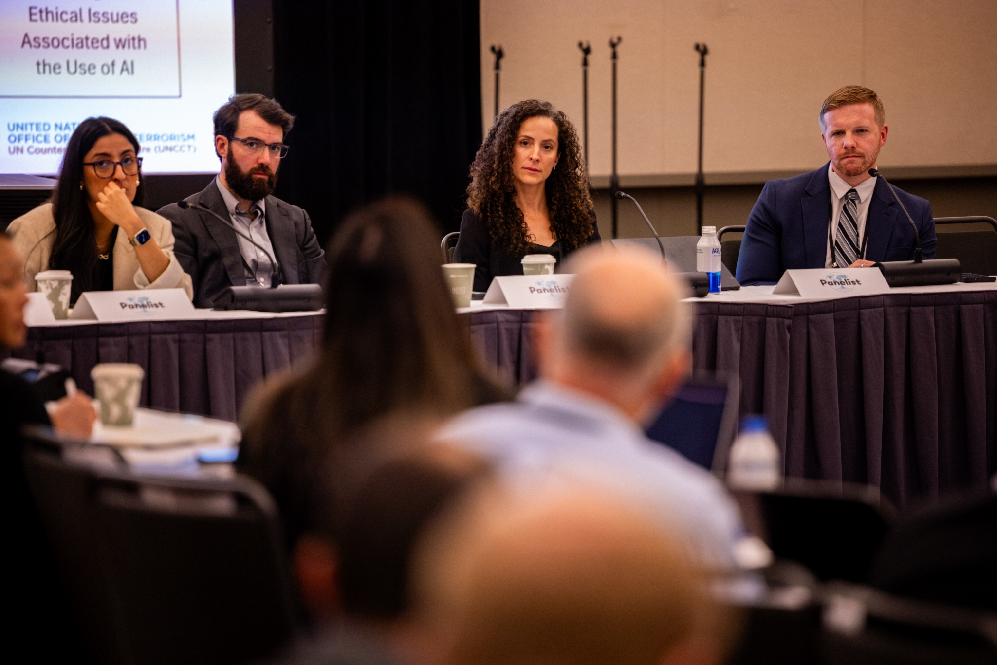 Four panelists sit at a long table during a conference discussion on ethical issues related to AI, facing an audience.