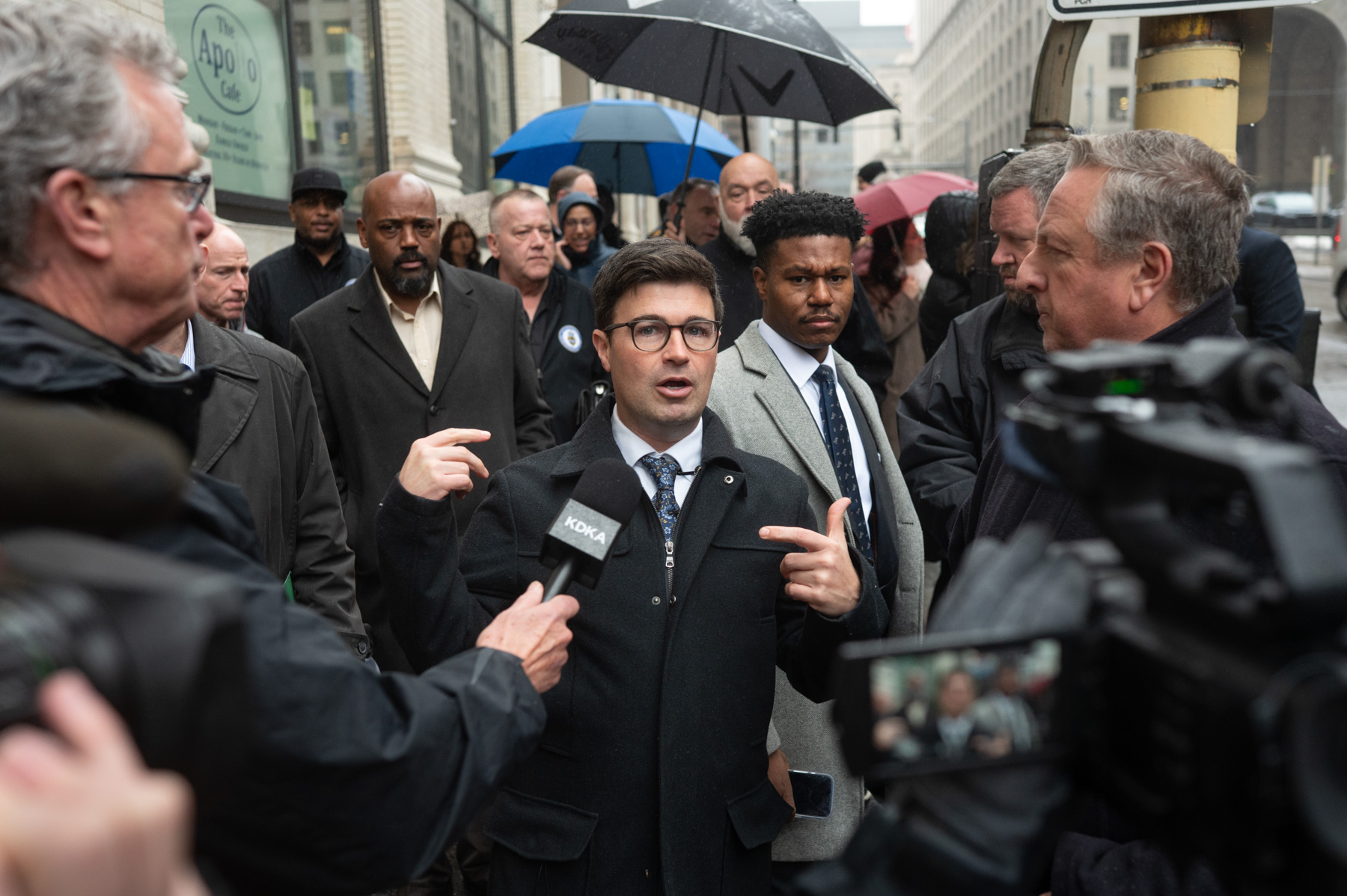 A man in a suit pointing at a microphone.