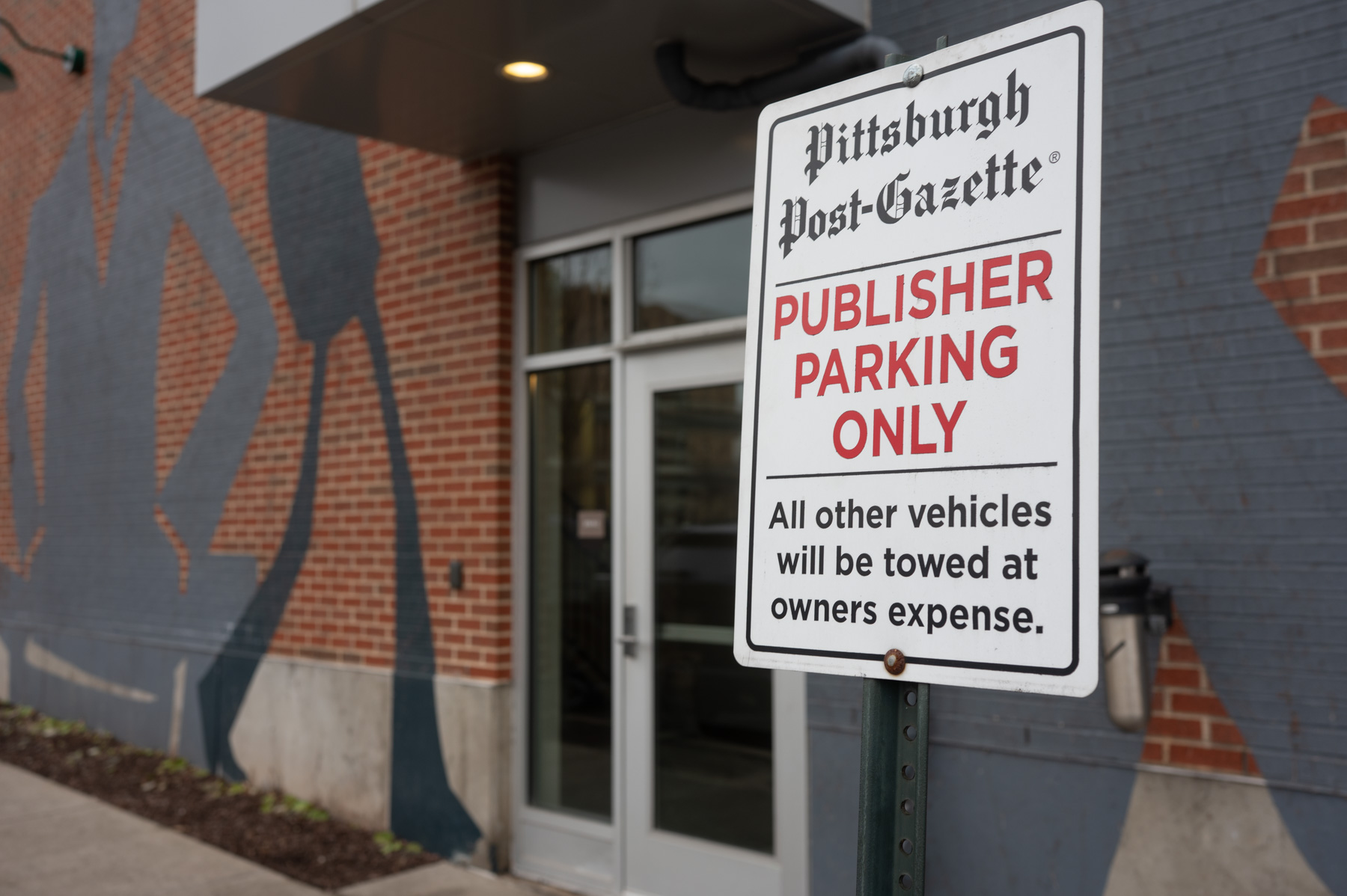 A sign in front of a brick building reads