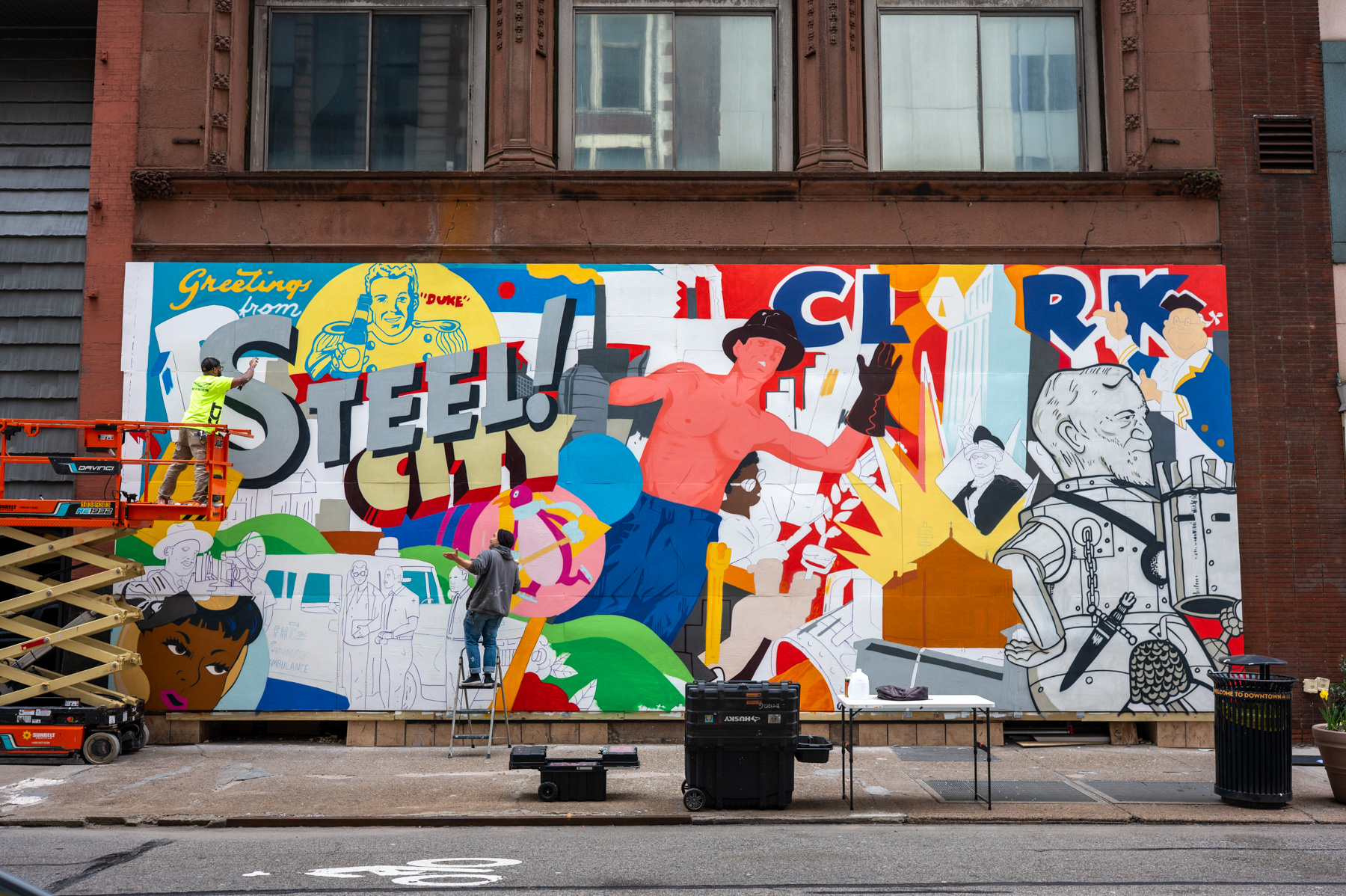 People work on a colorful mural that reads 