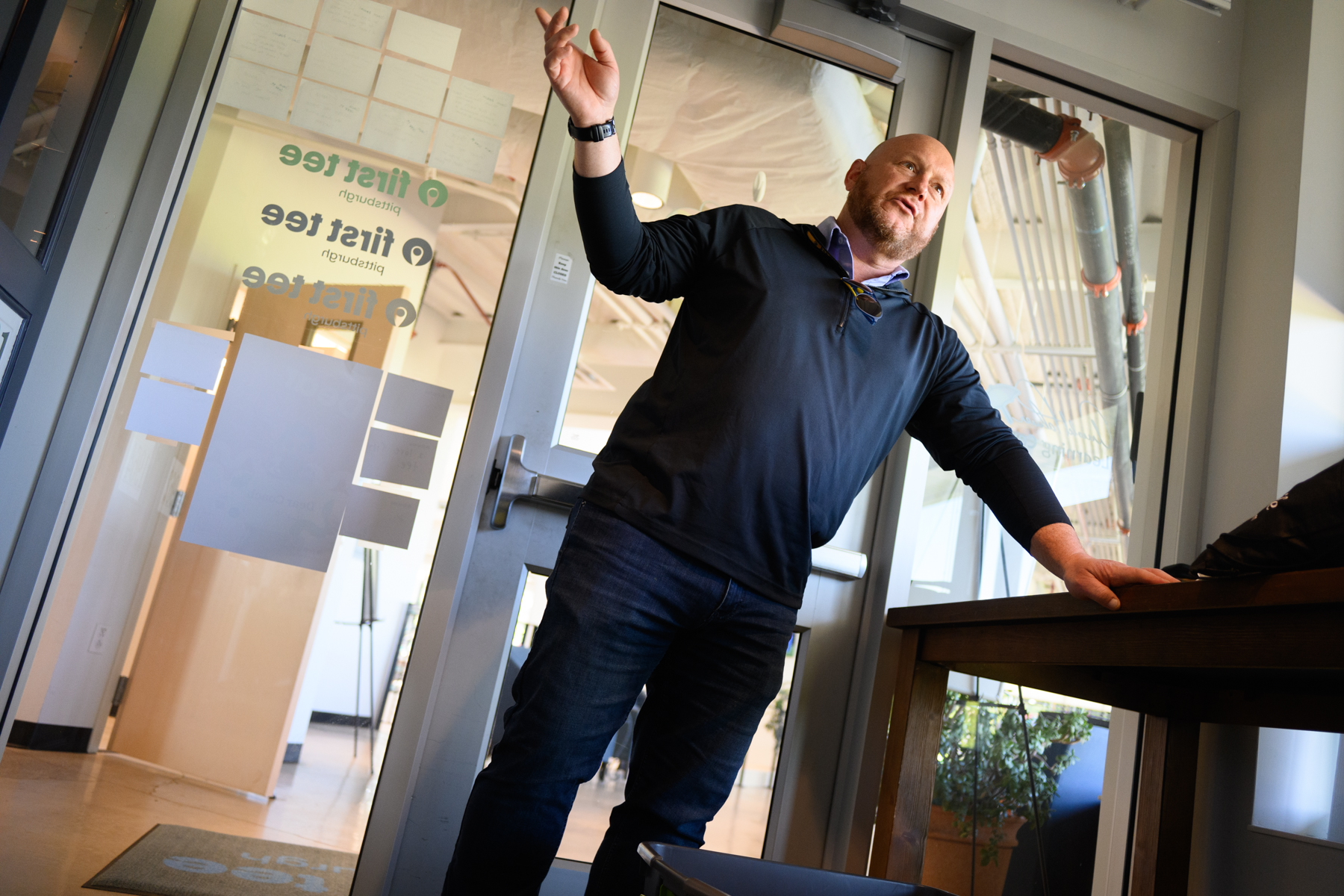 A man stands near a glass door labeled