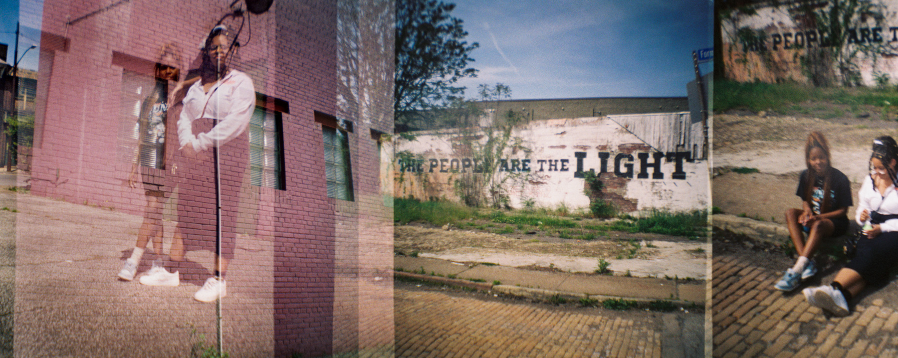 Double-exposed photo with a person standing by a brick wall, an empty lot, and a mural reading “THE PEOPLE ARE THE LIGHT,” plus two people sitting on a curb.