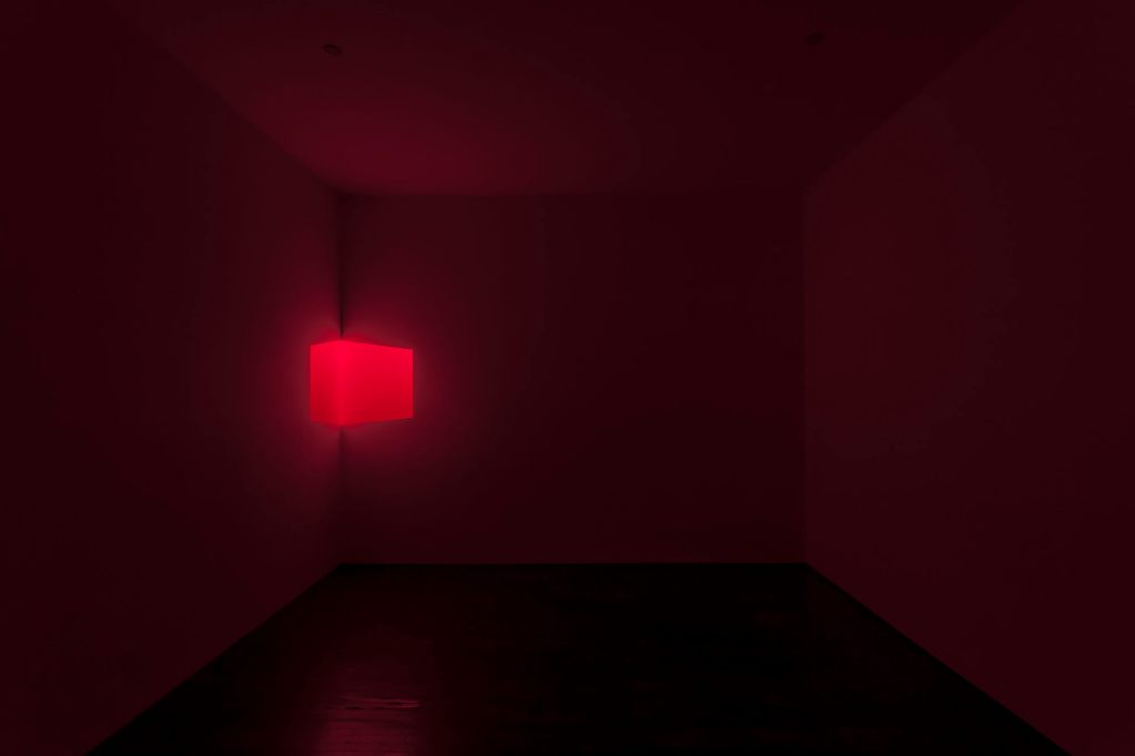 A red glowing box midway up the wall in the edge of a dark room.