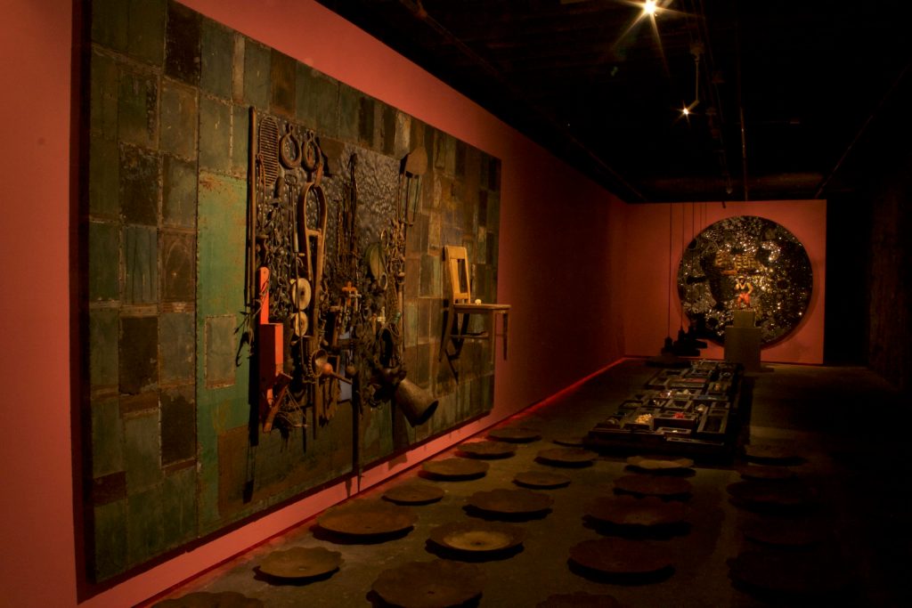 A collage of industrial metal materials on the wall and floor of a dark room.